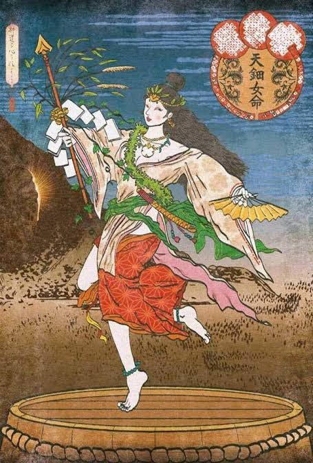 This illustration of Ame-no-Uzume portrays her with long lustrous black hair and a jeweled crown on her head shaped like the rising sun. The goddess is dressed in robes of red, pink, yellow, and green and dances on top of a wooden platform. 