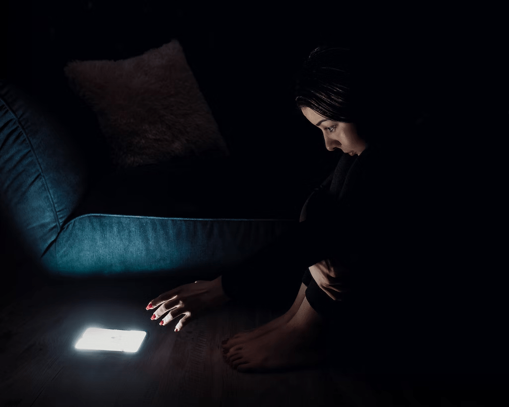 a woman sitting on the floor and reaching the phone