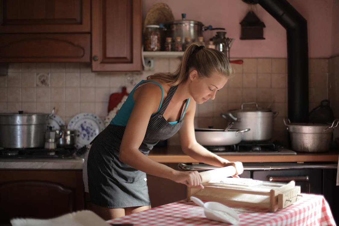 a woman in blue tank top using a rolling pin