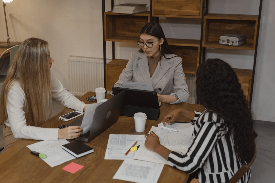 women having a meeting with 2 laptops on the table
