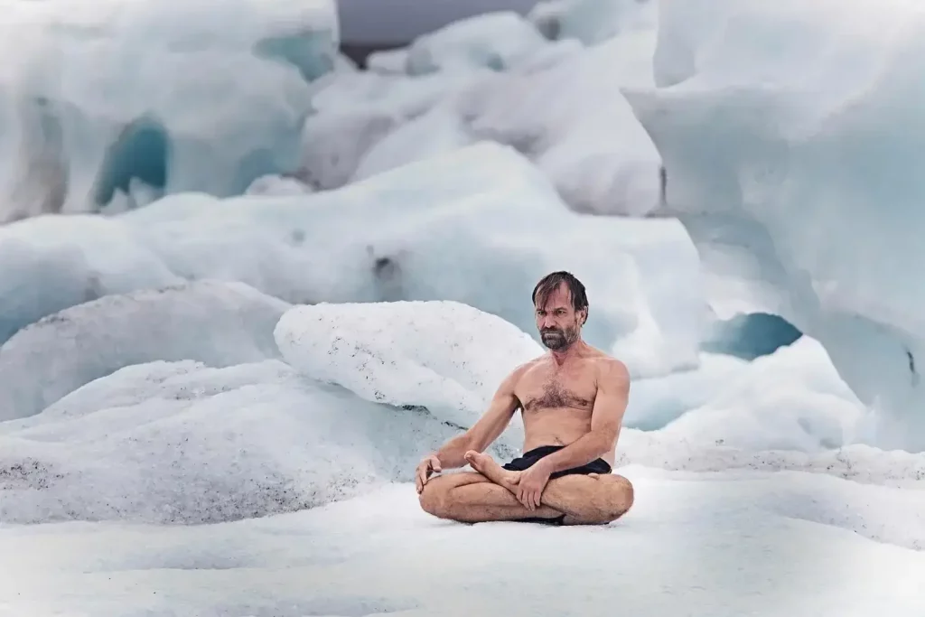Wim Hof meditating in lotus position on a snowy field, performing breathing exercise