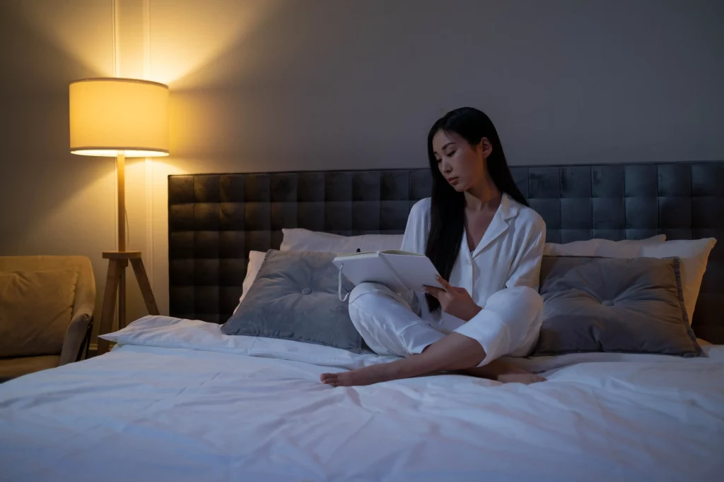 a woman sitting on a bed, writing in her journal