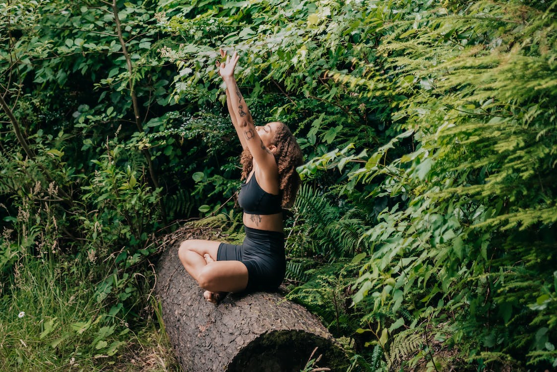 woman in black activewear doing yoga on a tree trunk