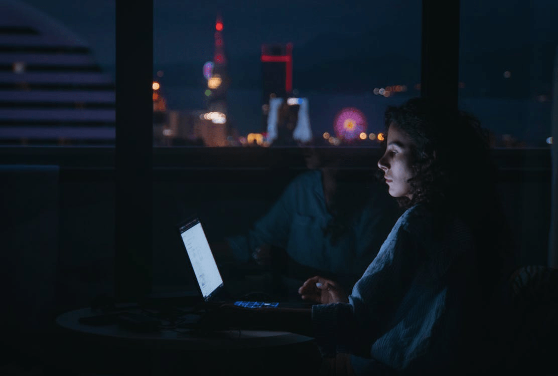 a woman looking at her laptop in the dark