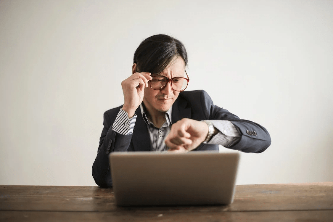 a confused businessman checking time on wristwatch
