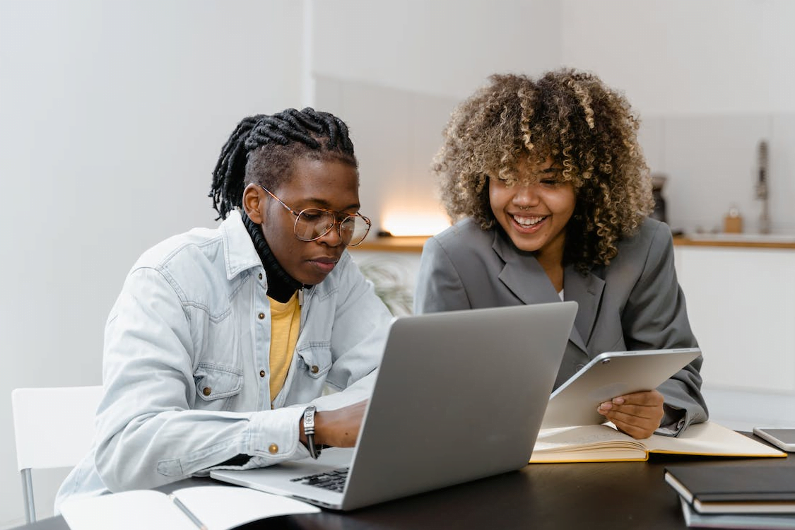 a man and woman having conversation while sitting in front the table with laptop