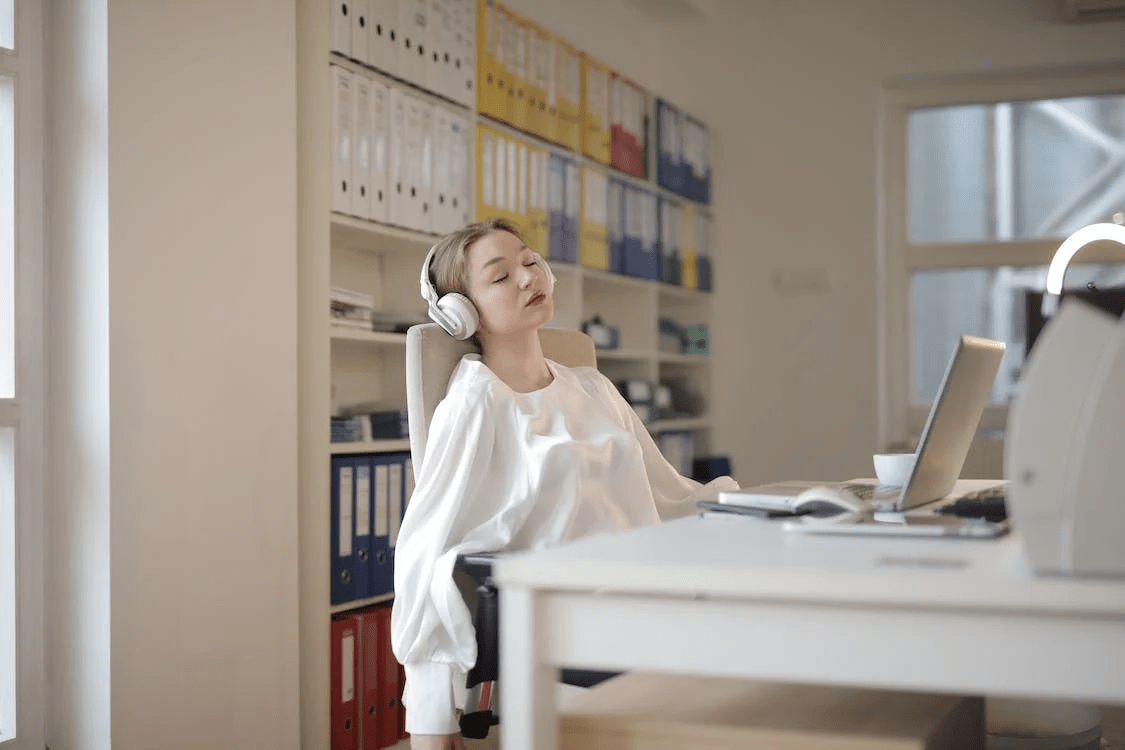 a woman in white sweatshirt sitting on chair in front of her laptop