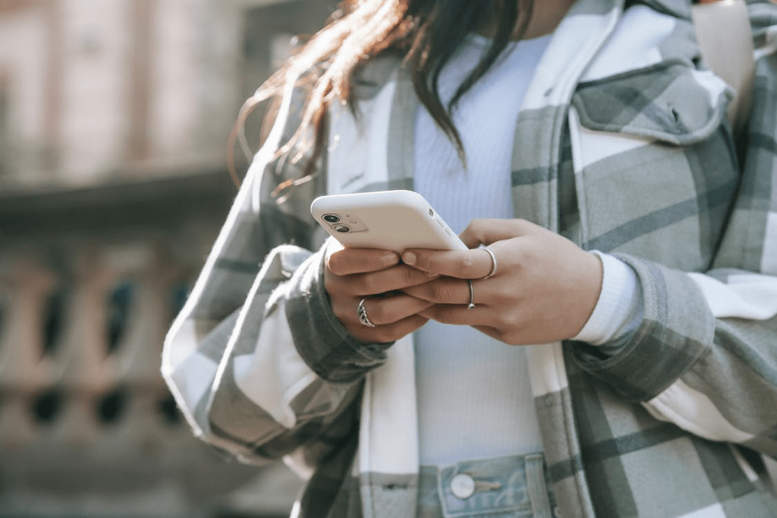 a woman in street typing on her phone
