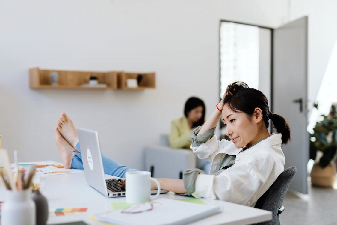 stressed woman using a laptop with her feet on the table