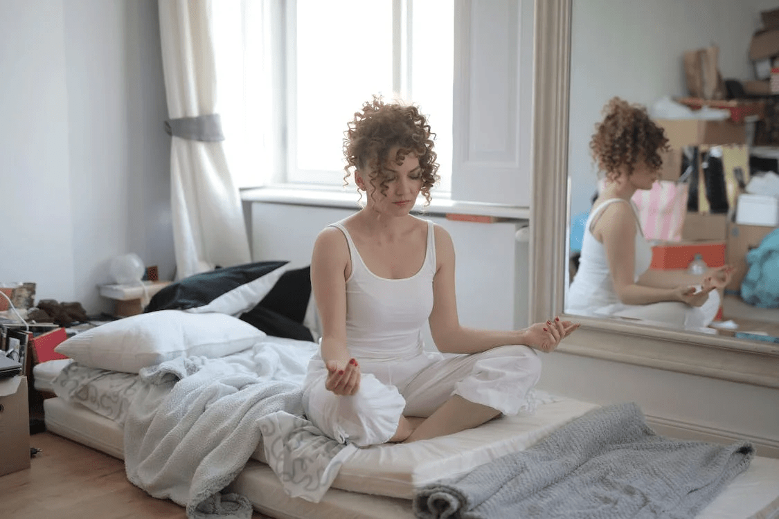 calm woman in lotus pose meditating at home