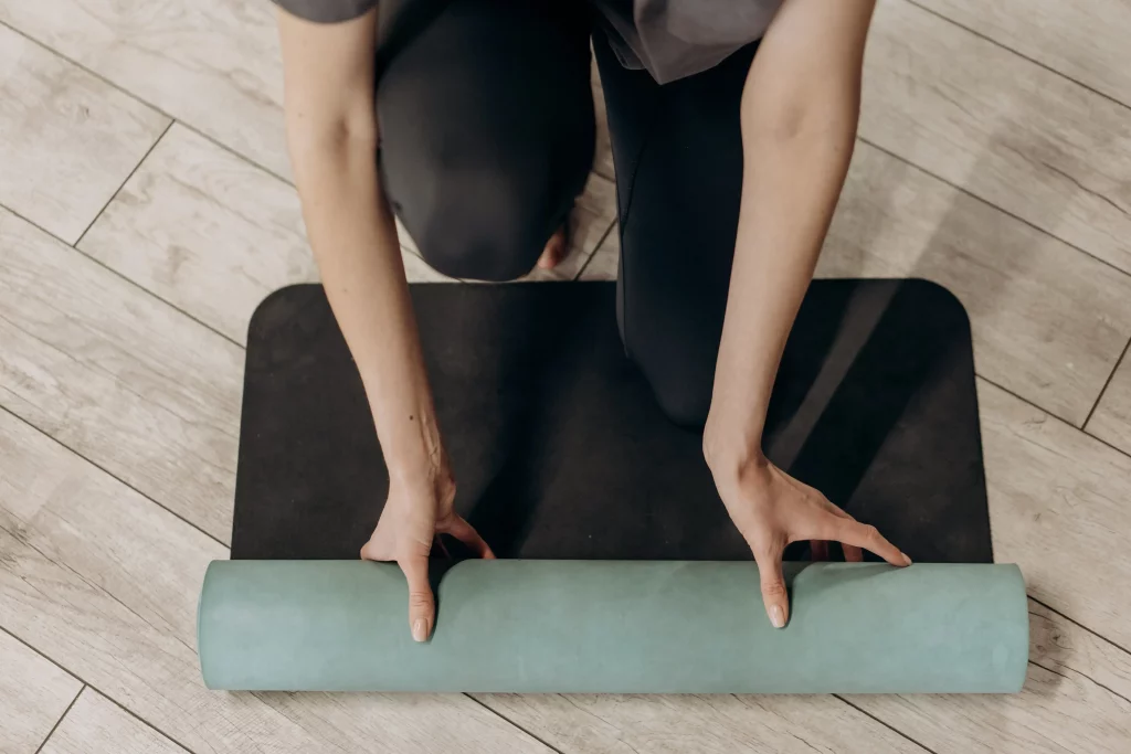woman in black leggings unrolling a yoga mat