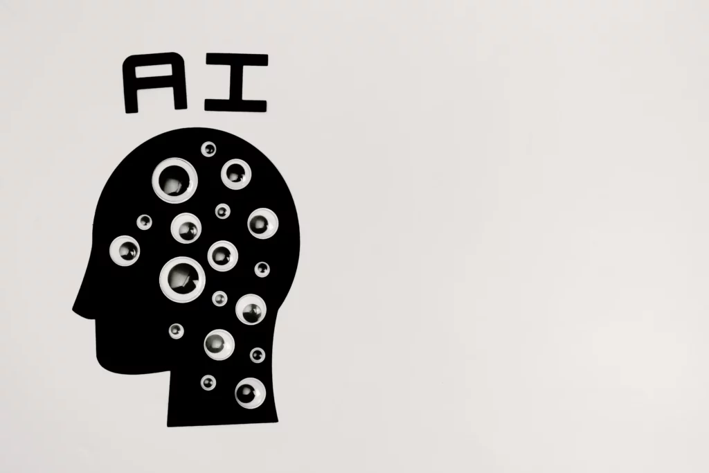 image of a black silhouette of a head, googly eyes, and 'AI' written in text 