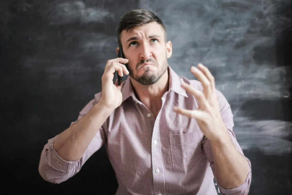 a frustrated man expresses anger while engaged in a phone conversation