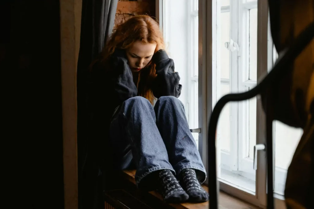 a woman sitting by the window with her head down