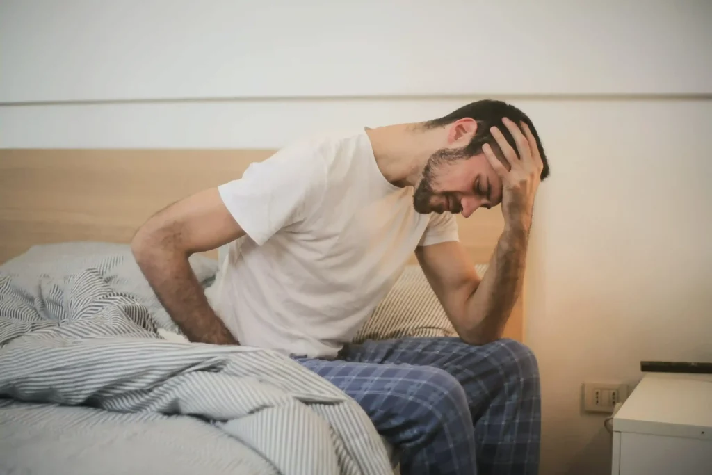 a young man in sleepwear suffering from headache in morning